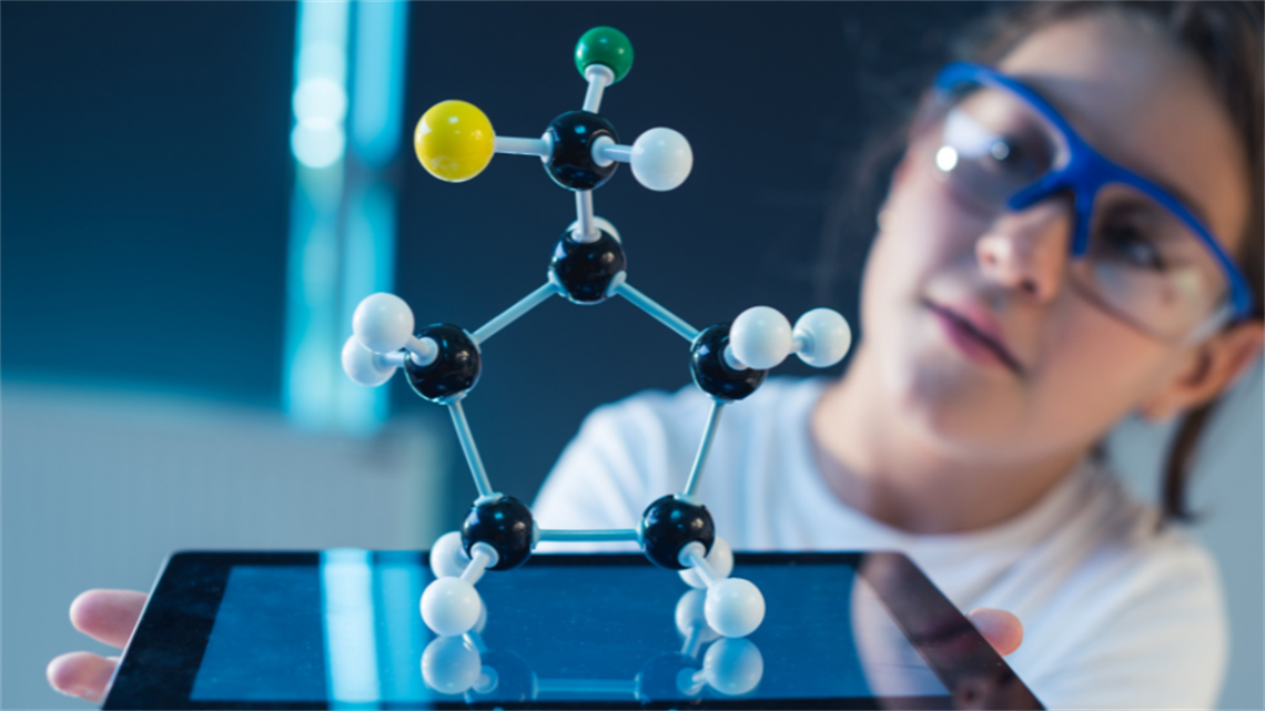 A girl holding a tablet with a science diagram on top