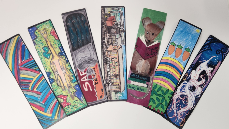 7 bookmark winning designs, a ran blue and yellow rainbow, a giraffe with green background, a half open tin of sardines, a steam train mobile library, a mouse made of feathers, a rainbow with three carrots, a white kitsune against a night sky