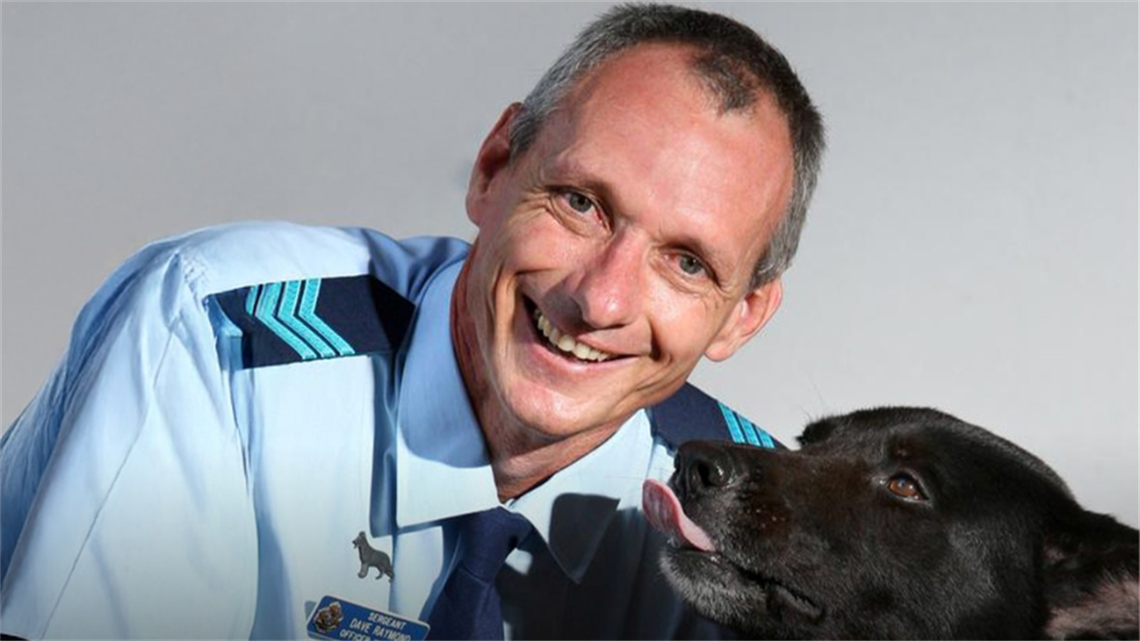 Headshot of David Raymond with police dog Vader