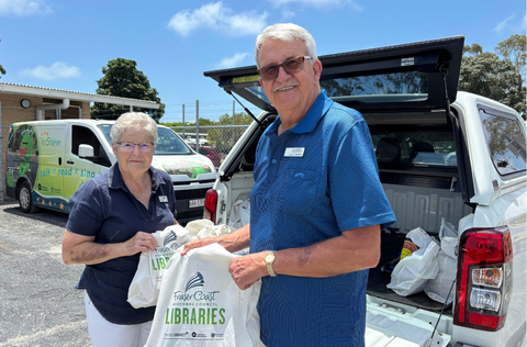 Volunteers with library bags in front of car smiling