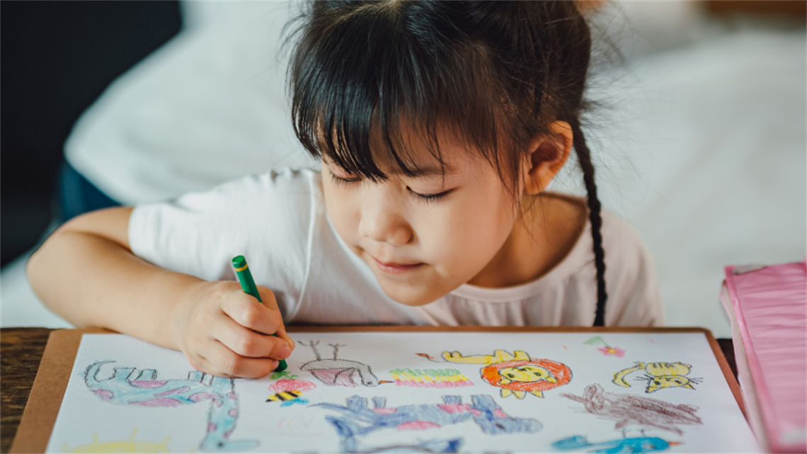 Child drawing multiple characters with a crayon