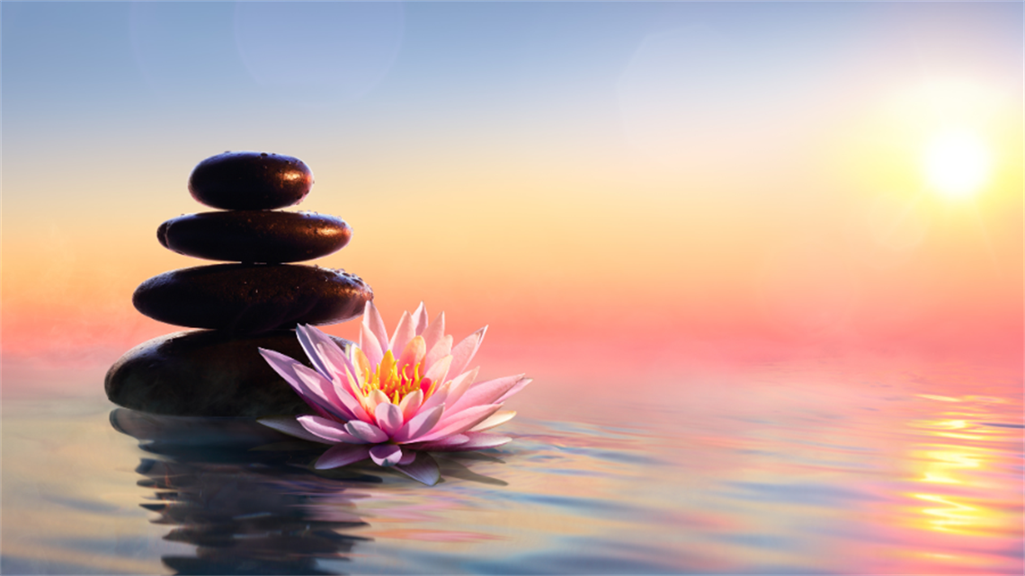 Four rocks balancing on top of one another on water with sunset in background