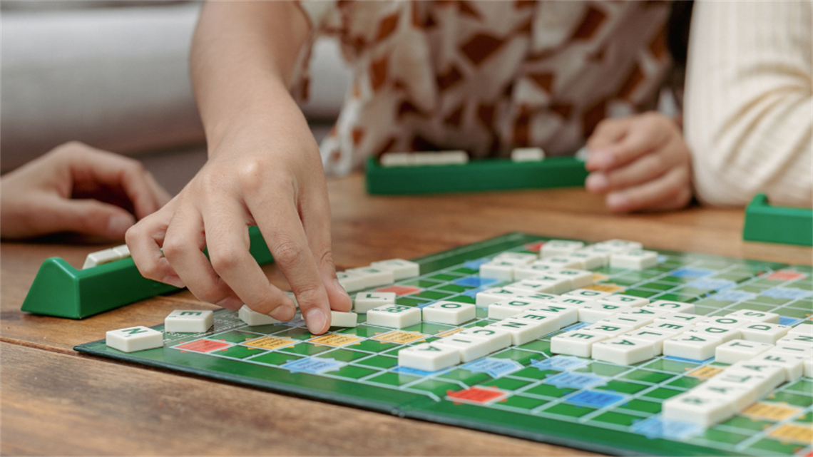 Close up of hands placing tile onto scrabble board